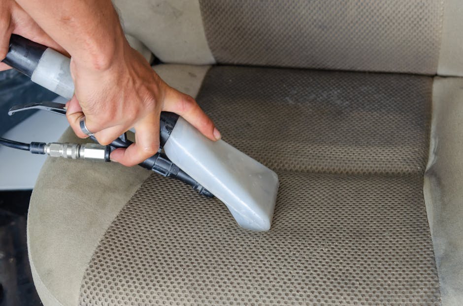 Two professional cleaners from Woodlands Carpet Cleaners are engaged in surface cleaning within a modern living room. The room features a light-colored wooden floor that appears well-maintained and fr